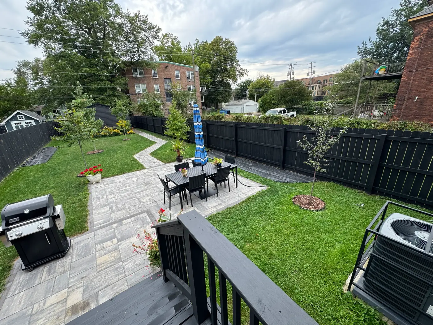 Backyard patio with paver hardscape, outdoor dining set, and freshly painted black fence and deck railing