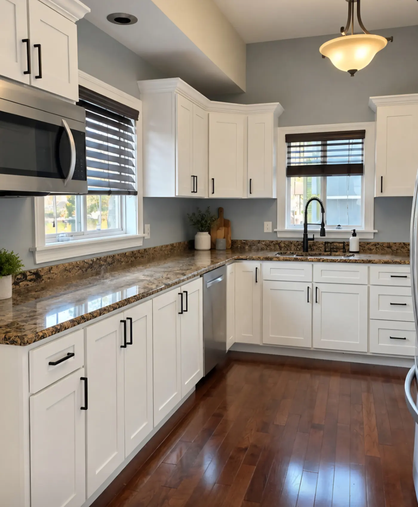 Kitchen after cabinet refinishing, with white painted cabinets, black hardware, and granite countertops