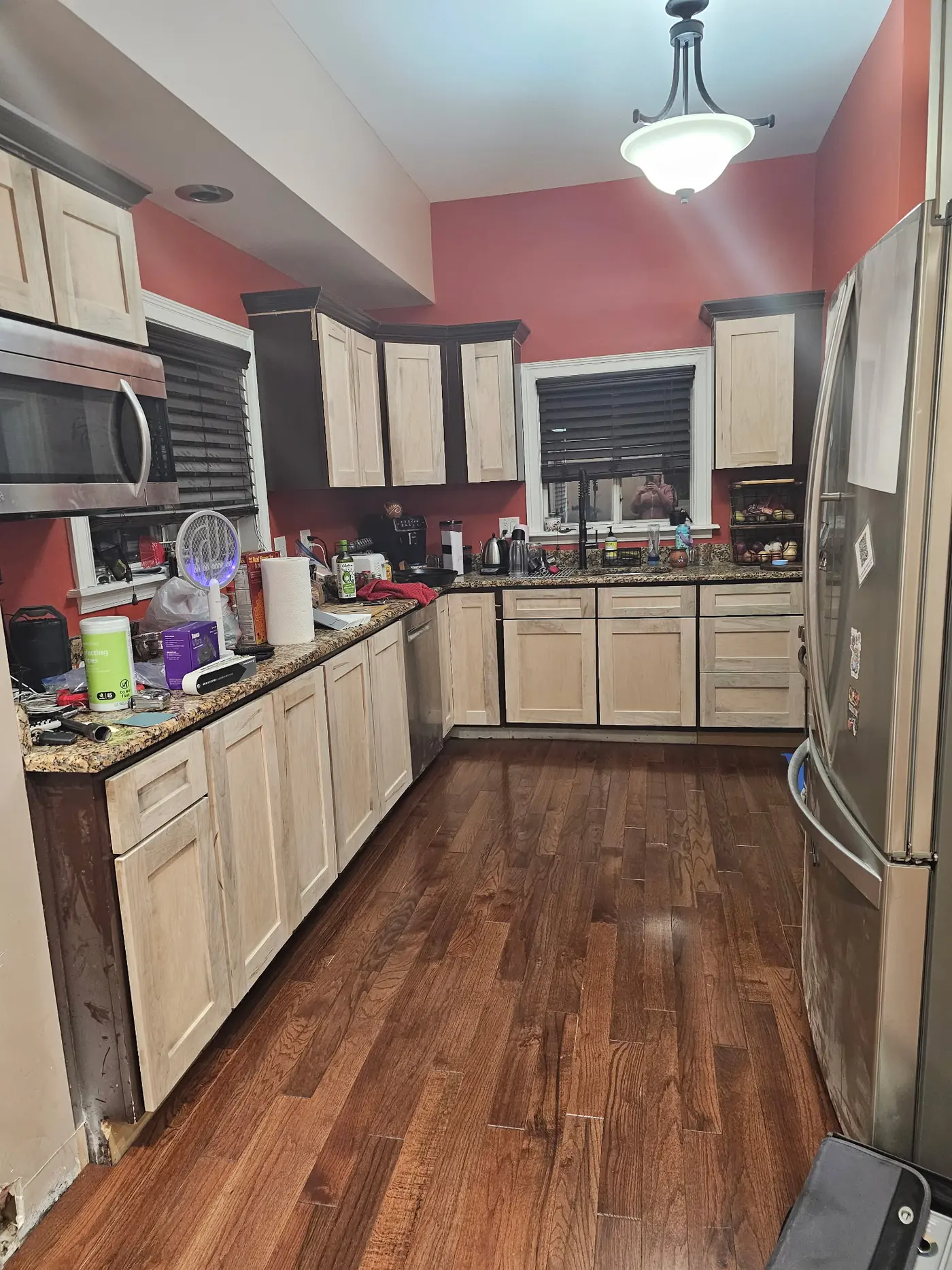 Kitchen before cabinet refinishing, with unfinished natural wood cabinets and red painted walls