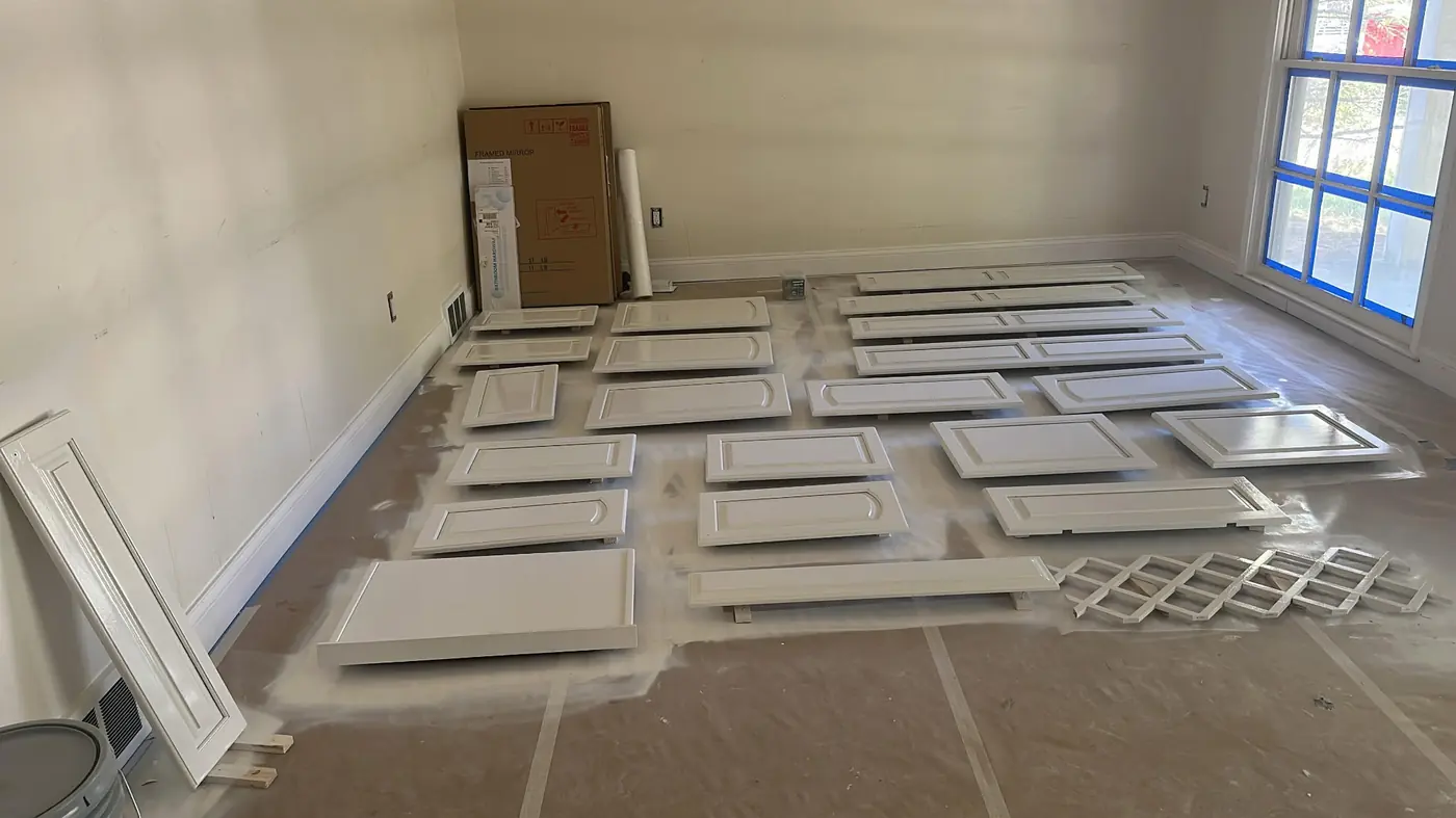 Cabinet doors and drawer fronts removed, primed, and laid out for refinishing