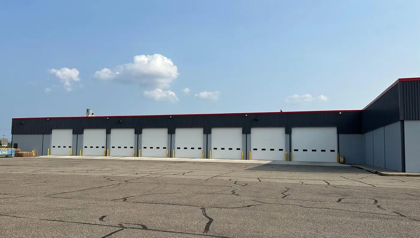 Commercial warehouse exterior with painted navy panels, red accent trim, and multiple loading dock doors