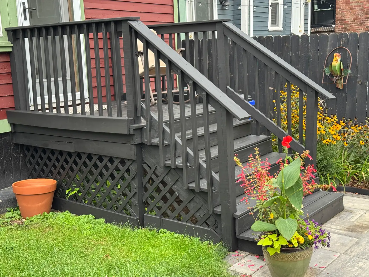 Freshly painted charcoal deck stairs and railing with surrounding landscaping