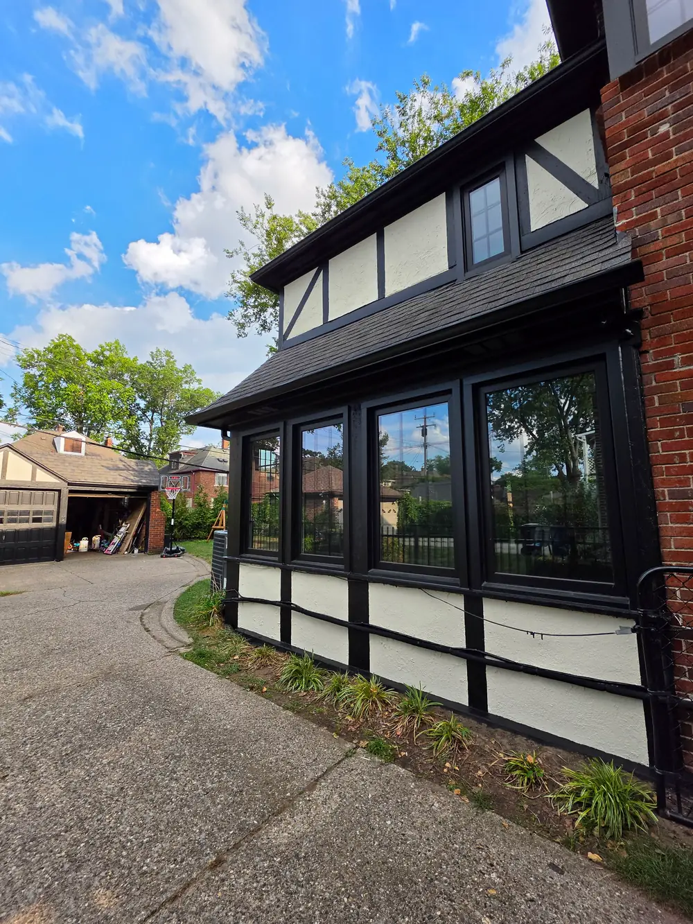 Tudor-style home exterior with black trim and cream stucco paneling
