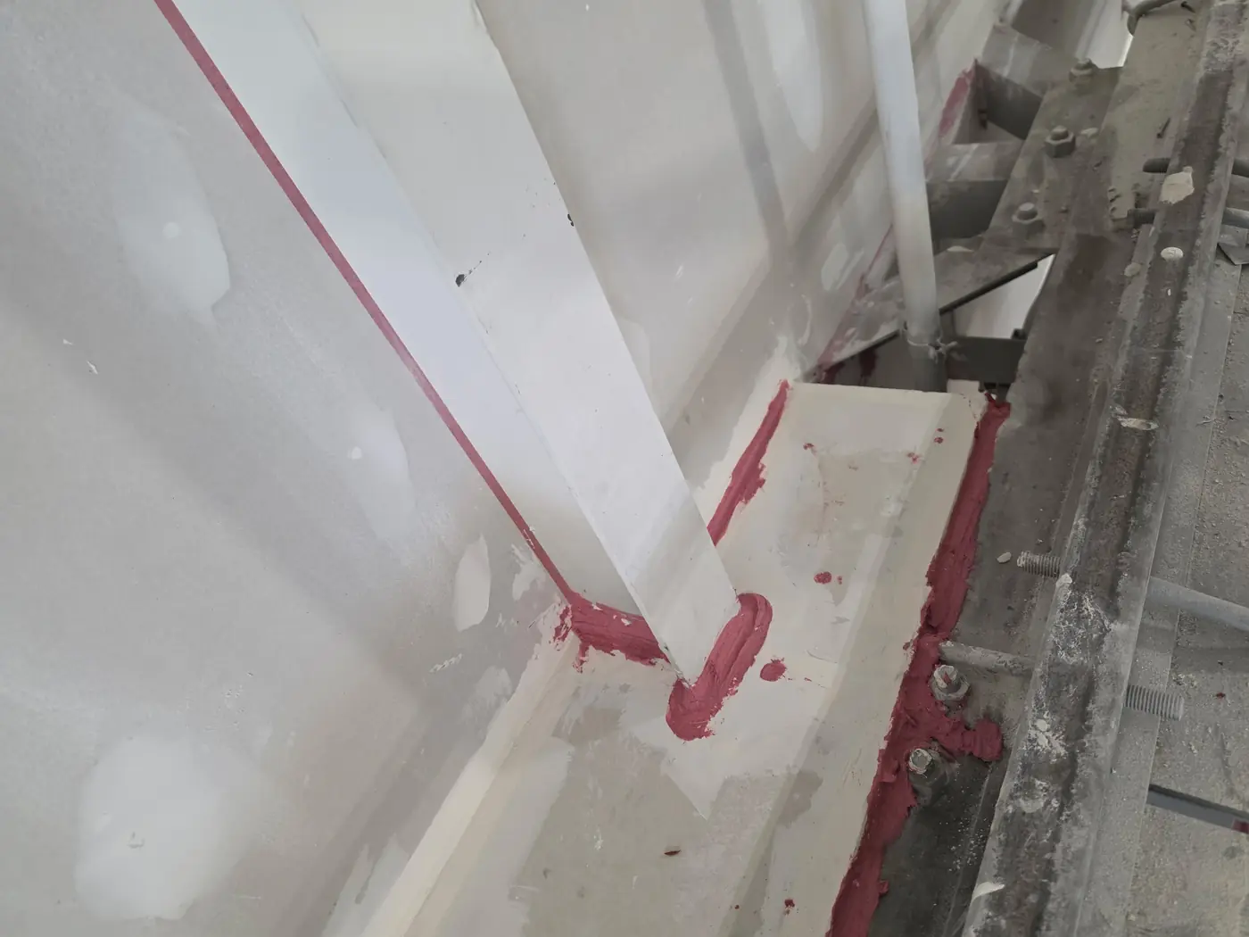 Close-up of fire-rated caulking applied at a steel and drywall joint