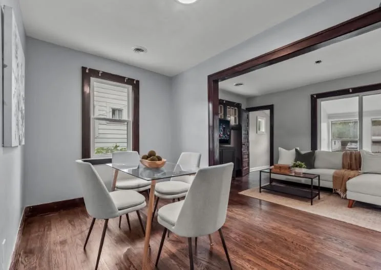 Freshly painted dining and living room with dark stained wood trim and hardwood floors