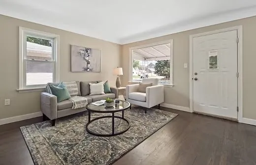 Freshly painted living room in a warm neutral tone with a gray sofa and dark hardwood floors