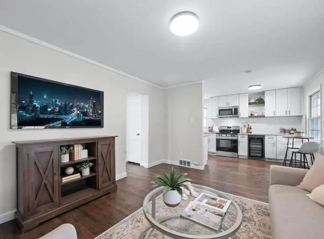 Open concept living and kitchen area with freshly painted walls and dark wood flooring