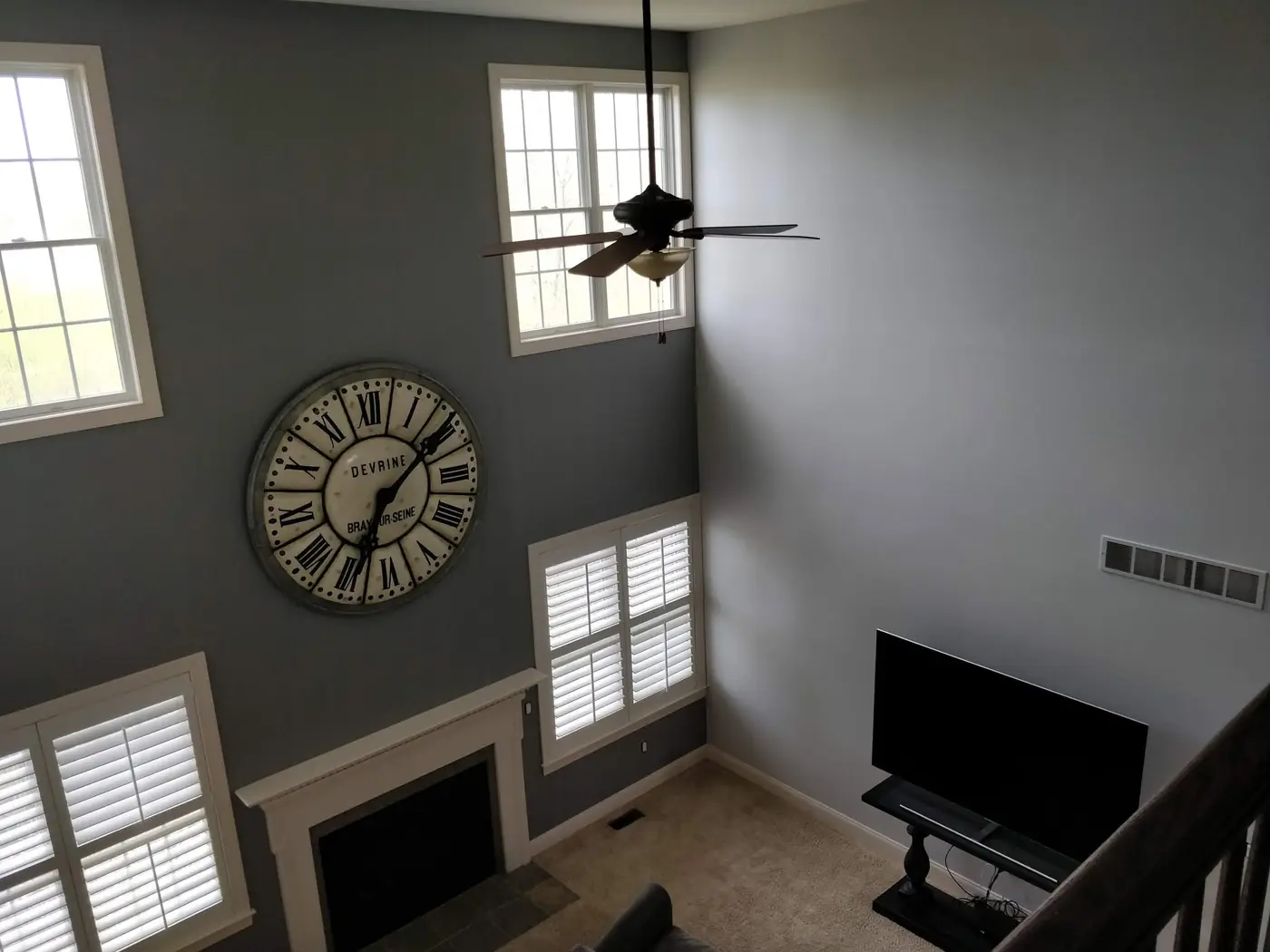 Vaulted living room with freshly painted gray walls, fireplace, and ceiling fan
