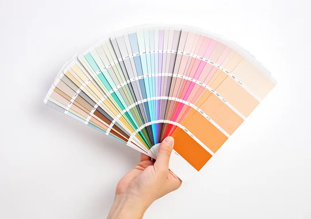 Hand holding a fanned-out selection of paint color swatches during a color consultation